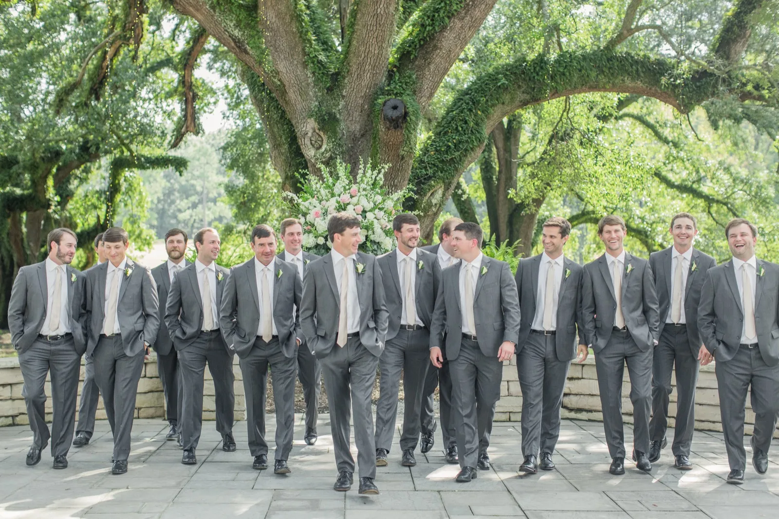 Fourteen groomsmen in coordinated gray suits walking together — Kinkade's Fine Clothing wedding party
